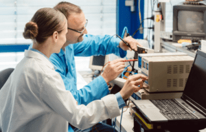 A female and male scientist electronically testing a machine.